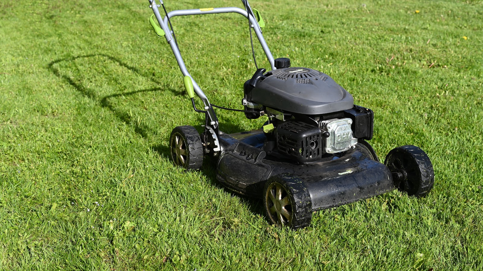 Rasenmäher im Einsatz auf gepflegtem Rasen — Symbol Gartenpflege